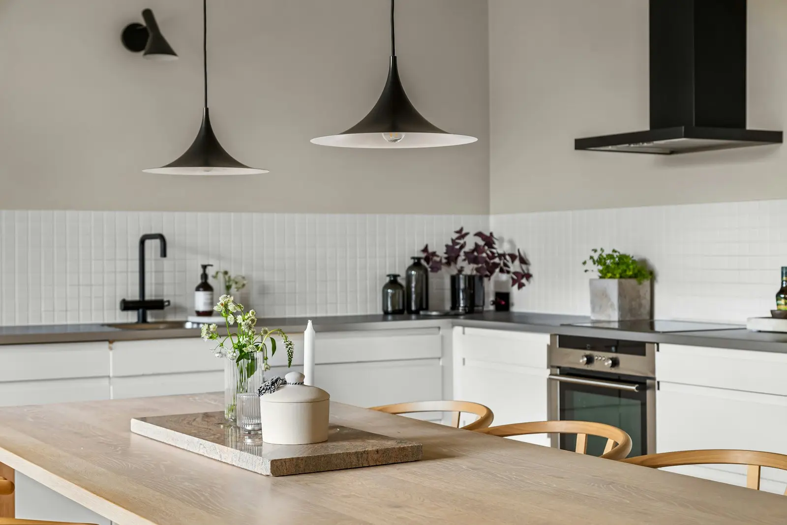 Kök med träbänk, vita luckor och pendellampor över bordet